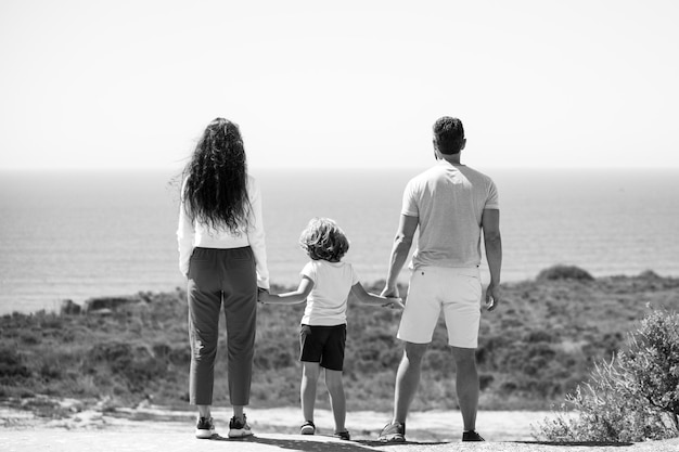 Boas férias em família pai alegre mãe bebê filho andar na praia de areia do mar pais e pessoas ativos