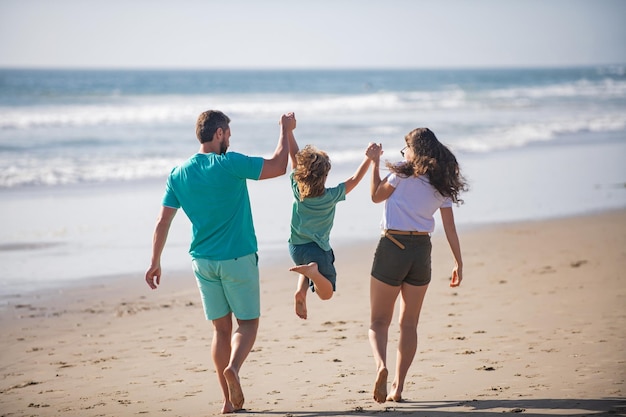 Boas férias em família Pai alegre mãe bebê filho caminhada de praia de areia do mar Pais ativos e pessoas atividade ao ar livre nas férias de verão com crianças Conceito de férias em família amigáveis