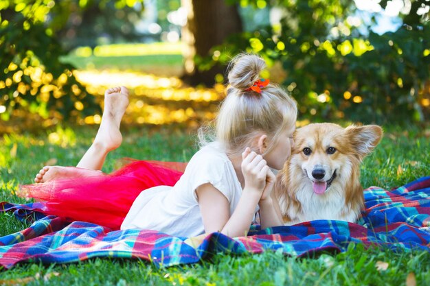 Boas festas divertidas - linda garota loira e corgi fofinho no gramado em um dia ensolarado de verão