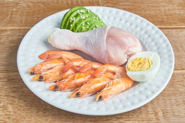 Boas fontes de gordura em um prato - frango, frutos do mar, ovo, abacate, gergelim. alimentação saudável e conceito de dieta cetogênica