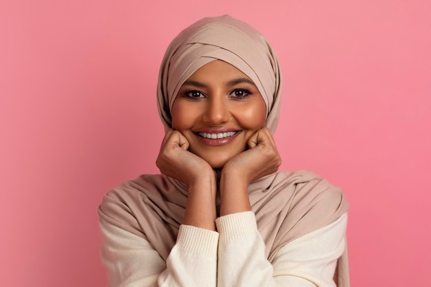 Boas notícias sonhadora jovem muçulmana em hijab descansando a cabeça nas mãos