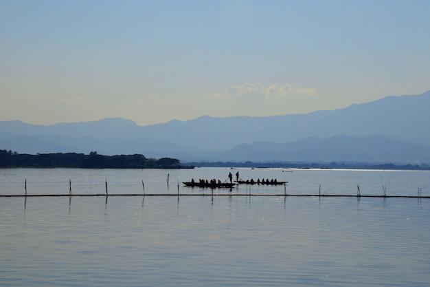 Foto boatman paddle para levar passageiros pelo vasto lago à noite em kwan phayao.