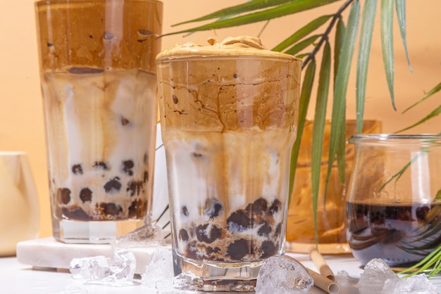 Boba Dalgona-Kaffee Trendiges asiatisches Latte-Morgengetränk mit geschlagenem Instantkaffee und Tapioka-Perlenkugeln Sommer-Thai-Bubble-Cocktailglas vor sonnigem Hintergrund