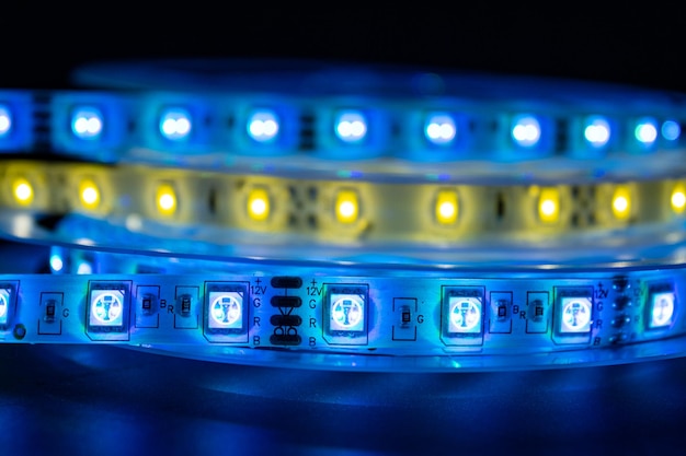 Bobbin com rolo de iluminação de faixa LED brilhante colocado na mesa de cor azul e branca quente