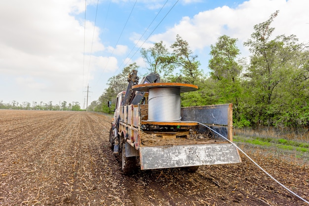 Foto bobina con cable de alta tensión montada sobre carretilla. instalación de cable sobre soportes de alta tensión