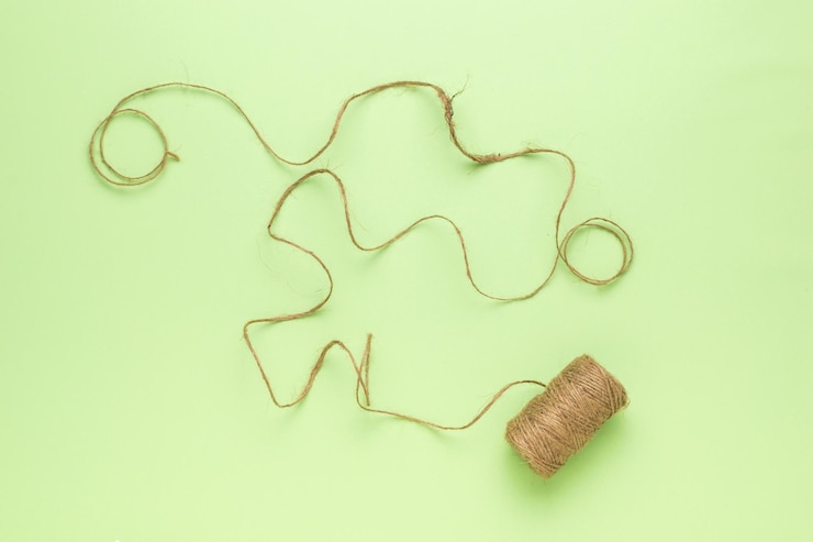 Foto una bobina desenrollada con una cuerda sobre un fondo verde
