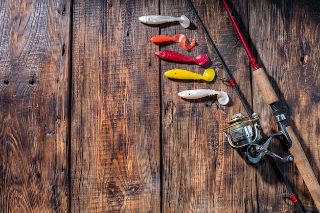 Foto bobina giratoria y señuelos de silicona suave composición de pesca en una tabla de madera señuelos en forma de pez vista desde arriba