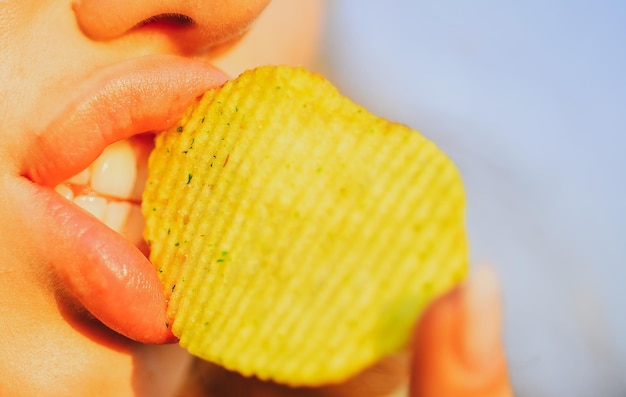 La boca de la chica del primer plano con placer come papas fritas