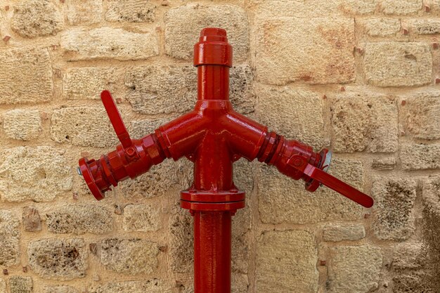 Boca de incendios roja cerca de la pared de piedra vintagexAxA