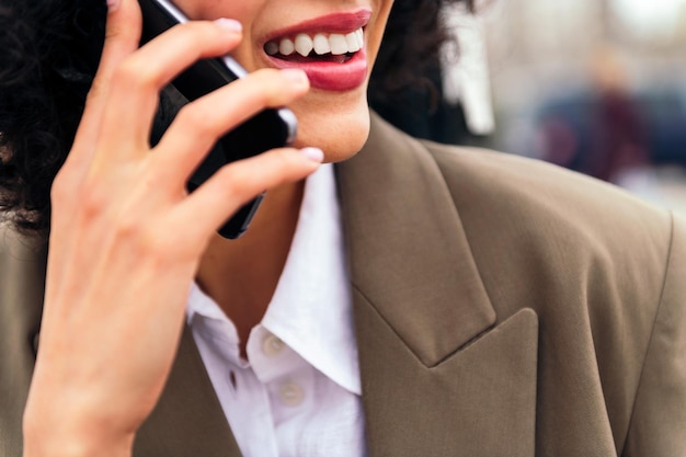 Boca de una mujer sonriente hablando por teléfono móvil