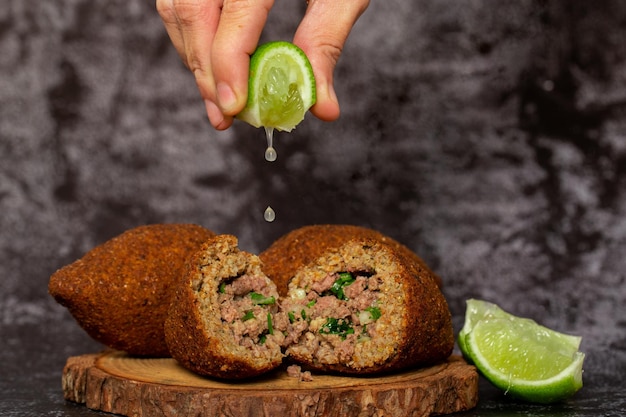 El bocadillo árabe tradicional de kibbeh en Brasil llamado Quibe Kibe servido con limón