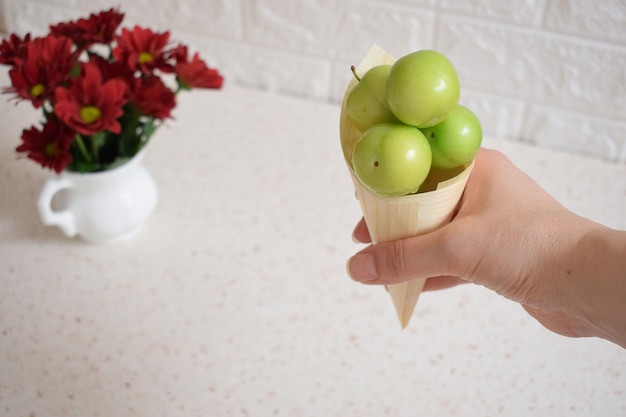 Un bocadillo con ciruelas verdes frescas en la mano de una joven