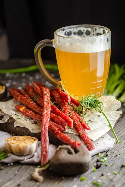 bocadillos de carne para cerveza, junto a un vaso de cerveza, papas fritas en una sartén, sobre una mesa rústica de madera
