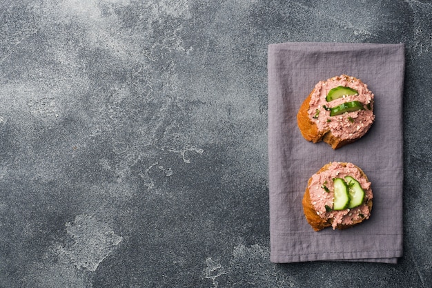 Bocadillos con la coronilla y el pepino de pollo en la tabla oscura.