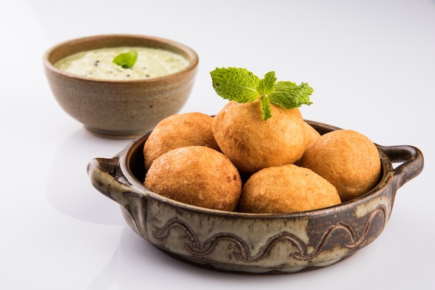 Bocadillos indios Aloo Bonda o batata vada o urad daal vada o pakoda o pakora. Servido con chutney verde. Enfoque selectivo