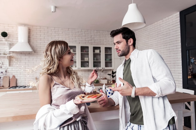 Bocadillos Linda mujer joven de pelo largo con bonito maquillaje sosteniendo un plato con sándwiches