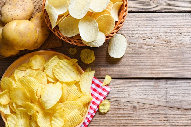 Bocadillos de papas fritas en un tazón y plato Papas fritas crujientes en la mesa de la cocina y papas crudas frescas sobre fondo de madera