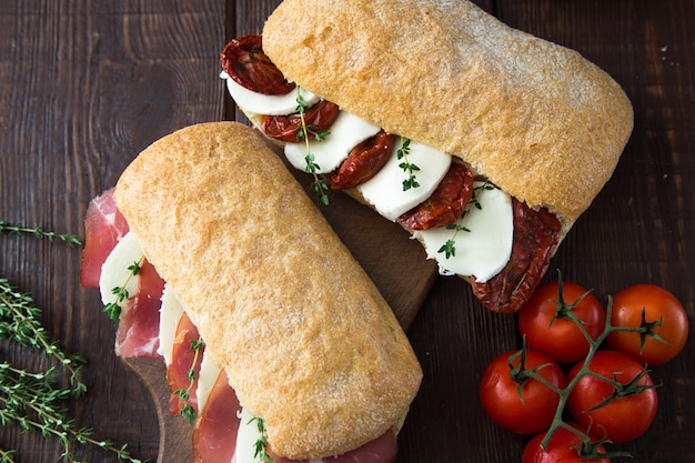 Bocadillos surtidos. Sándwich Caprese con mozzarella y tomates secos y ciabatta con jamón