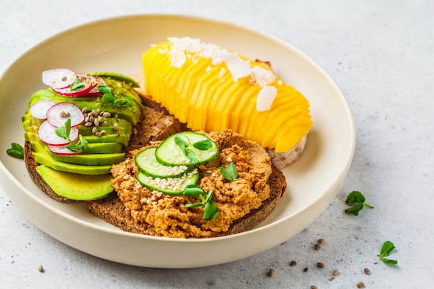 Bocadillos veganos con mango, aguacate y tofu en un plato blanco.