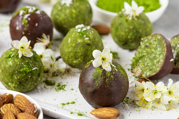 Bocaditos o bolas de Matcha Energy en glaseado de chocolate con flores. Postre de snack saludable vegano crudo. de cerca