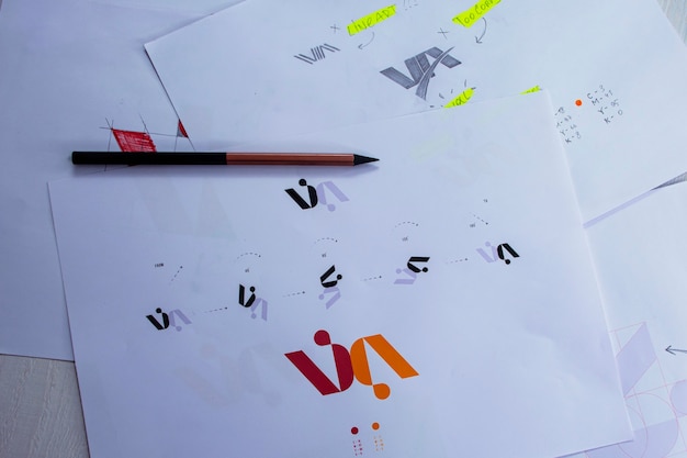 Bocetos y dibujos del logo impresos en papel. Desarrollo de diseño de logo en el estudio sobre una mesa.