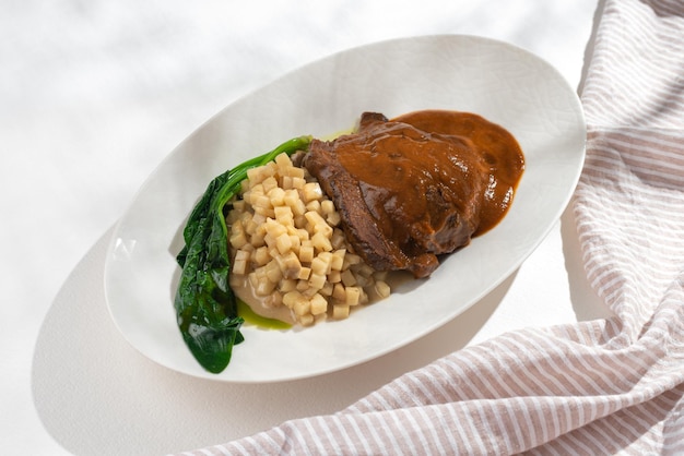 Bochechas de carne assada alemã tradicional em molho de vinho tinto marrom com risoto de aipo em fundo branco