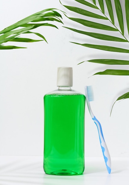 Bochechos refrescantes em uma garrafa de plástico transparente e uma escova de dentes em um fundo branco
