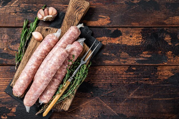 Bockwurst Salsichas cruas com carne de porco em uma placa de madeira. Fundo de madeira escuro. Vista do topo. Copie o espaço.