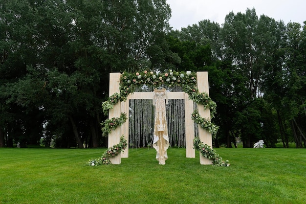 Boda al aire libre de un parque Un hermoso vestido está colgado en el arco de la boda Vista frontal