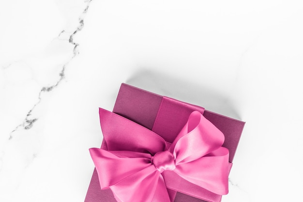 Foto boda de cumpleaños y concepto de marca femenina caja de regalo rosa con lazo de seda sobre fondo de mármol niña b ...