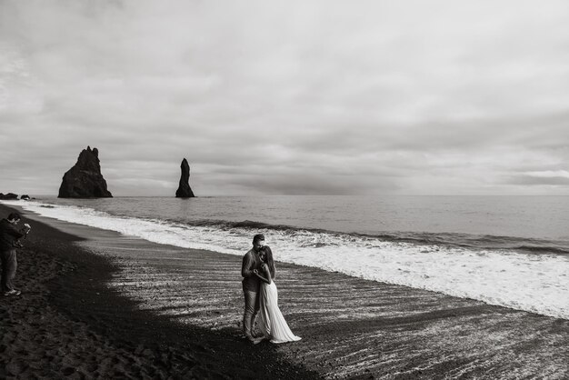 Boda de destino Islandia. Una pareja de novios pasea por la playa negra de Vic.