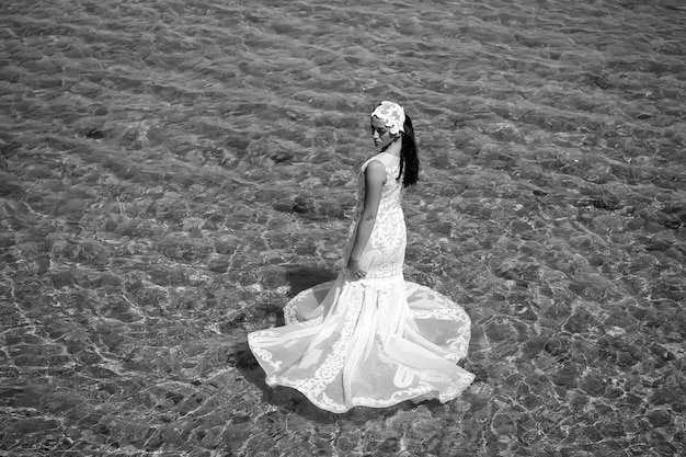 Boda en el extranjero Ceremonia de boda a orillas del mar Novia vestido de novia blanco de pie en agua de mar Vestido de novia mojado caliente día soleado Novia feliz disfrutar de vacaciones de verano fondo del océano Luna de miel en el mar resort