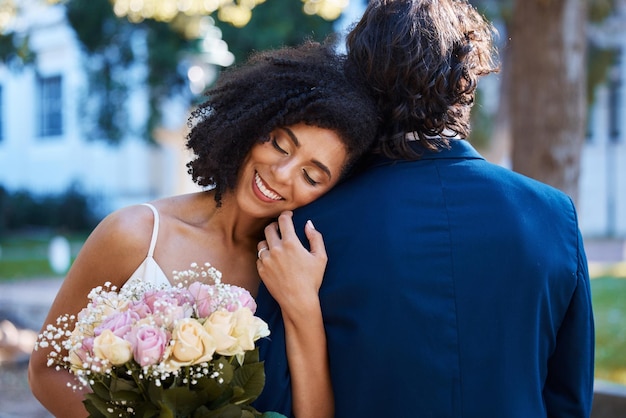 Boda feliz novia y pareja al aire libre para el evento de celebración del matrimonio junto con compromiso Hombre y mujer casados interraciales en la ceremonia con asociación de confianza y un abrazo con ramo de flores