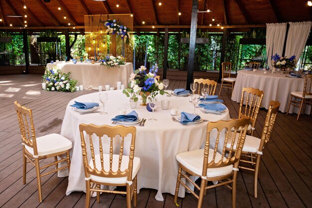 Boda festiva, mesa con servilletas de lino azul, velas, sillas doradas y ramos de flores frescas. Decoraciones de boda. Concepto de menú de restaurante. Enfoque selectivo suave.