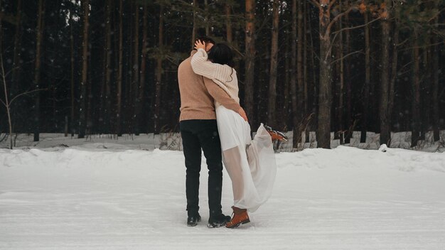 boda de invierno. jóvenes abrazándose por la espalda en el invierno en el bosque