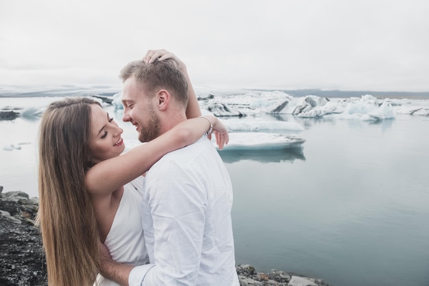 Boda en Islandia. Un chico y una chica con un vestido blanco se abrazan mientras están de pie sobre un hielo azul