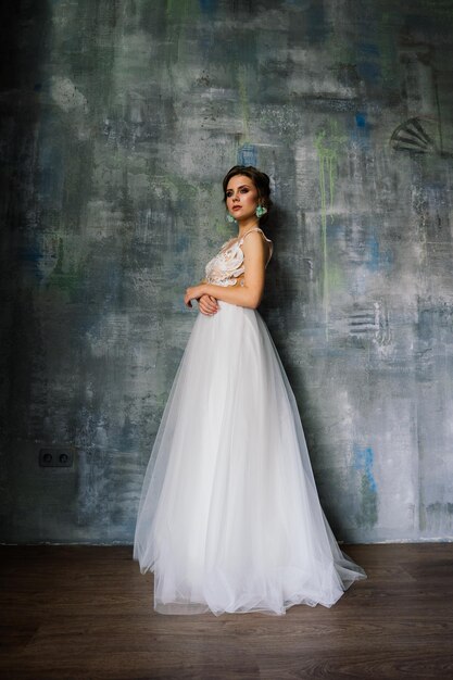 Boda. Novia con un hermoso vestido en el interior de un estudio blanco como en casa.