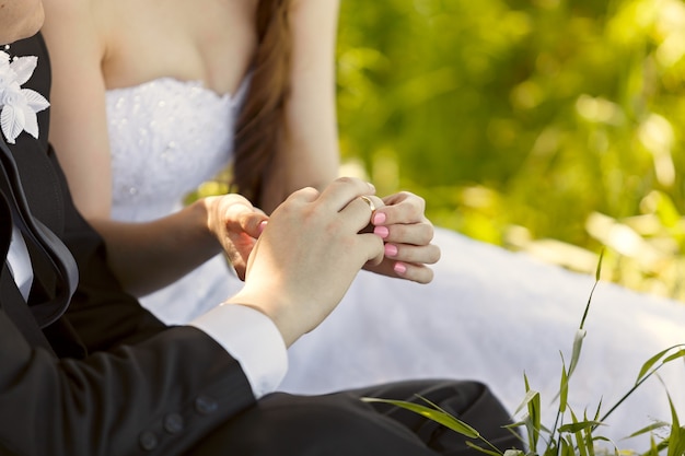 En la boda, la novia se pone el anillo en el dedo del novio. Mano del novio y la novia con anillos de boda en una fiesta de bodas. Al aire libre