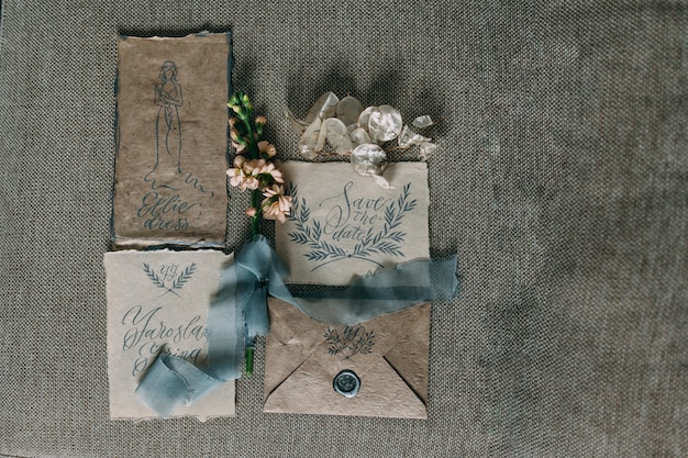 Boda rústica y artes gráficas de hermosas tarjetas de caligrafía con flores y bobinas de gasa. Invitación de boda hermosa vista superior.