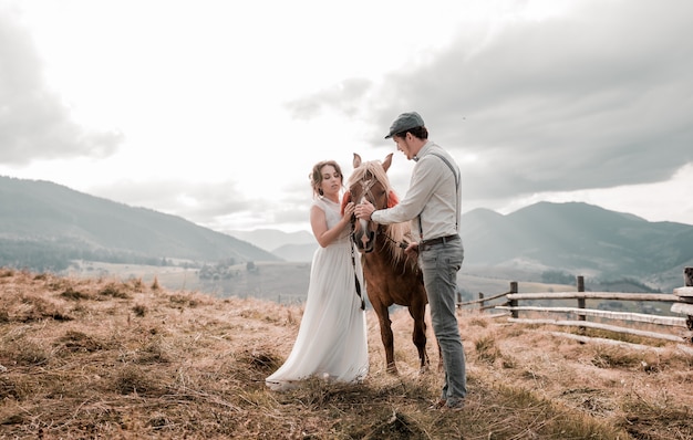 Boda vintage de novios en un rancho con un caballo en las colinas de pico