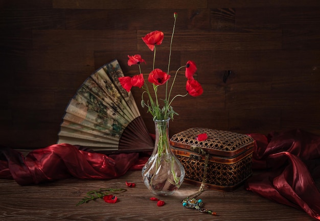 Foto bodegón con abanico un ramo de amapolas y joyas colgante con piedras semipreciosas estilo rústico