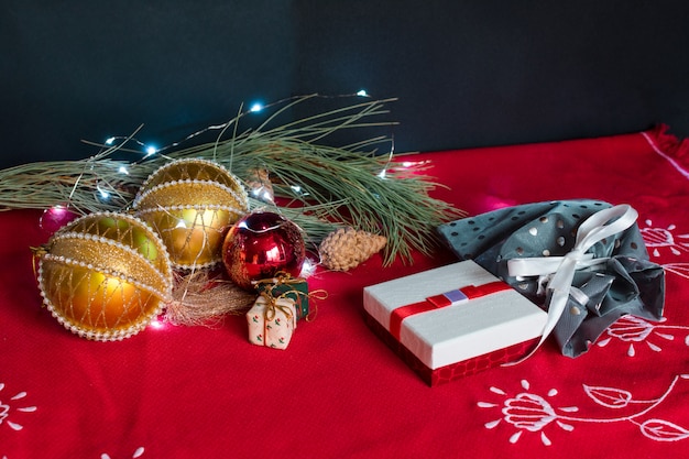 Bodegón de accesorios de navidad sobre fondo negro y mantel rojo