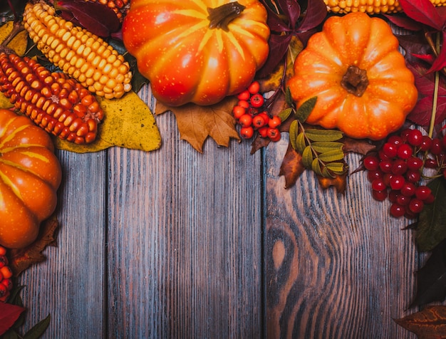 Bodegón de acción de gracias - bayas, nueces, maíz y calabazas en una mesa