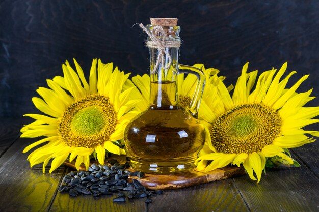 Bodegón con aceite de girasol en botella de vidrio, semillas y girasol