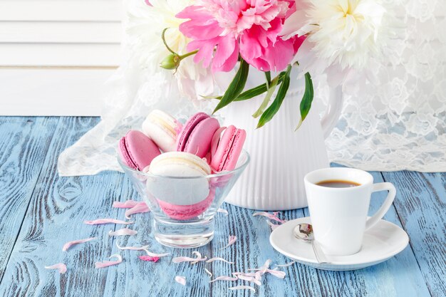 Bodegón artístico con peonías y taza de café y pétalos.