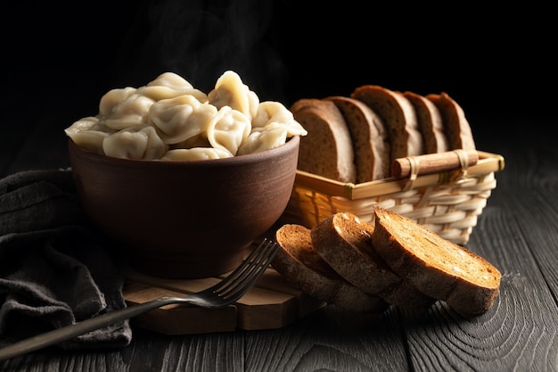 Bodegón con bolas de masa hervida calientes en un cuenco de barro y pan de centeno tostado