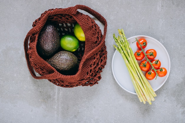 Bodegón de bolsa de compras biodegradable marrón con verduras crudas en gris