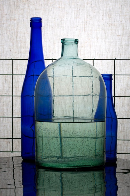 Bodegón con botellas azules y una jarra con agua.