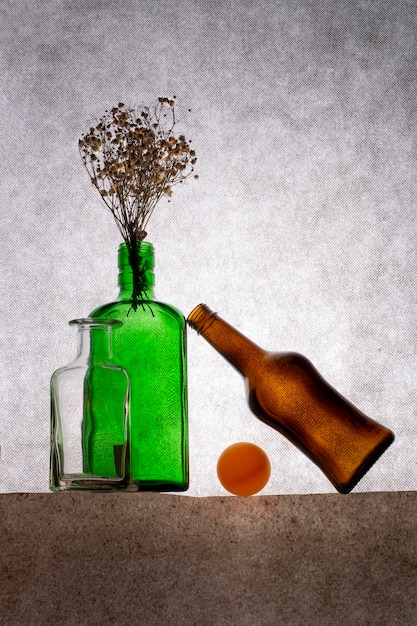 Bodegón con botellas de colores y ramitas de plantas secas