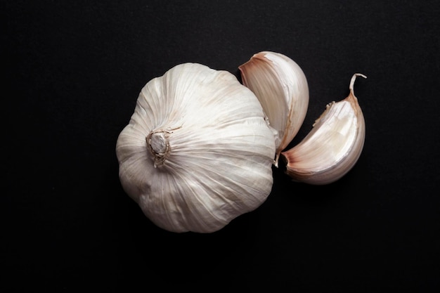 Bodegón de cabezas de ajo y dientes de ajo sobre fondo negro concepto de comida de ingredientes saludables